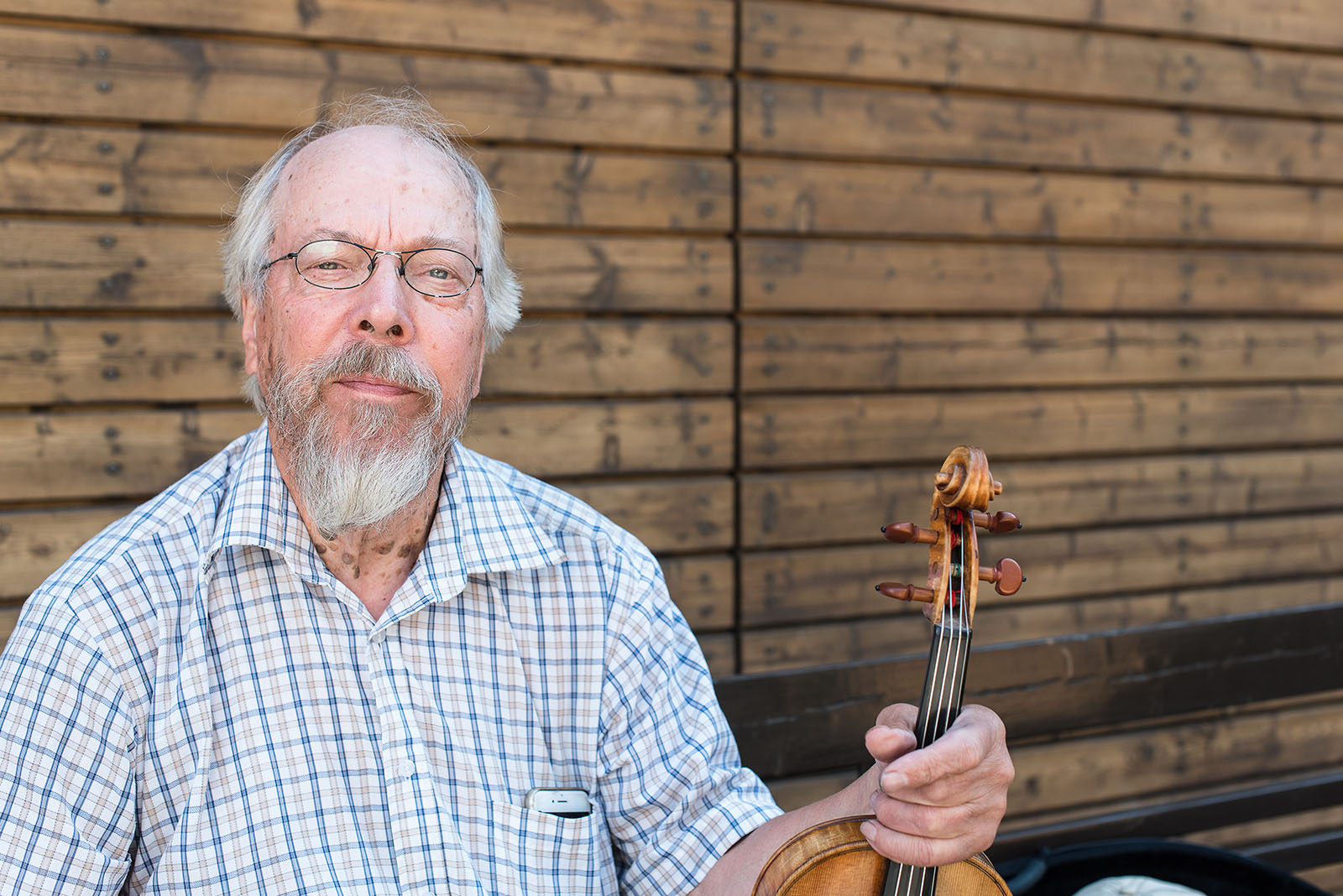 Mauno Järvelä istuu viulun kanssa penkillä.