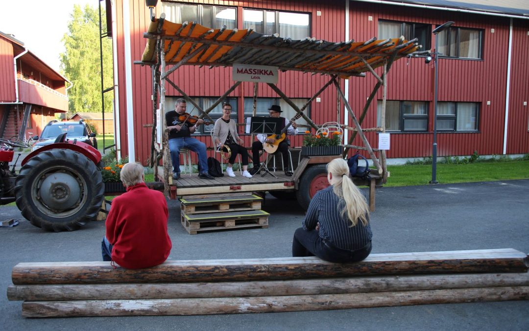 Kaustisen kansanmusiikkijuhlien traktorin peräkärrylle tehdyllä lavalla kolme pelimannia esiintymässä.