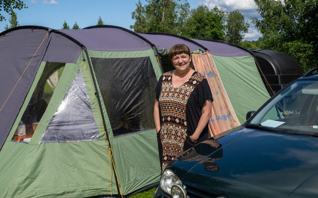 Nainen teltan ja auton välissä.